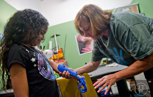 Ty Esham (right) helps 10-year-old Anastasia Rivas try out her new robohand assistive device at Esham's office in Decatur on Tuesday, August 5, 2014. 
