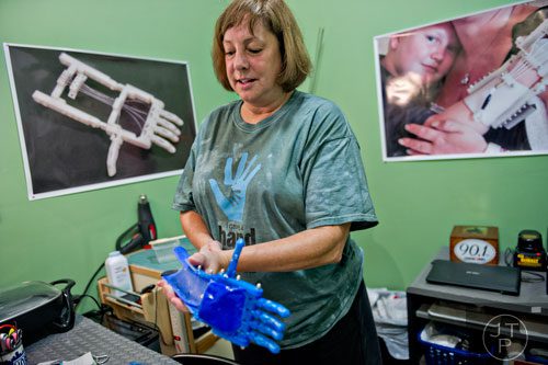 Ty Esham shows 10-year-old Anastasia Rivas her new robohand assistive device during a fitting session at her office in Decatur on Tuesday, August 5, 2014.  