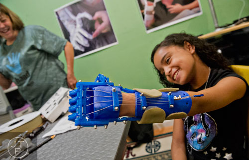 10-year-old Anastasia Rivas (right) tries out her new robohand assistive device in Ty Esham's office in Decatur on Tuesday, August 5, 2014.  