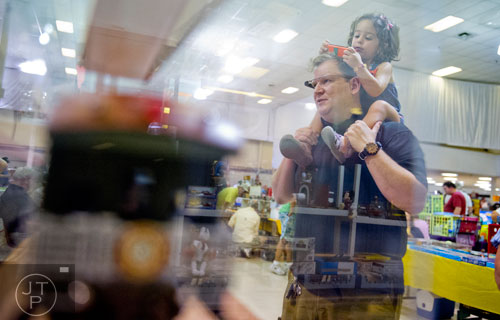 Zoya Starbird (right) holds a train car as she sits on her father Ray's shoulders as they look at different displays during the 47th Atlanta Model Train and Railroadiana Show and Sale at the North Atlanta Trade Center in Norcross on Saturday, August 9, 2014. 