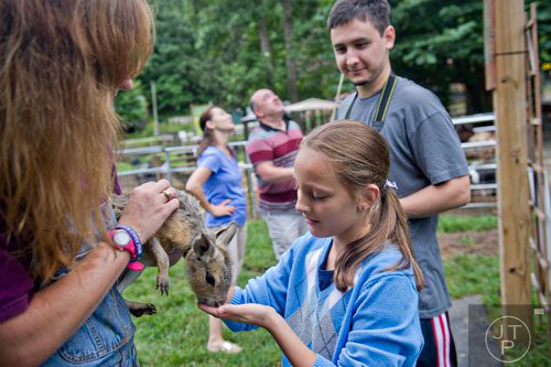 Evelyn Krakovski (right) checks out a Patagonian mara held by Shannon Kelly (left) as he brother Lev watches at the North Georgia Zoo and Petting Farm in Cleveland on Sunday, August 10, 2014. 