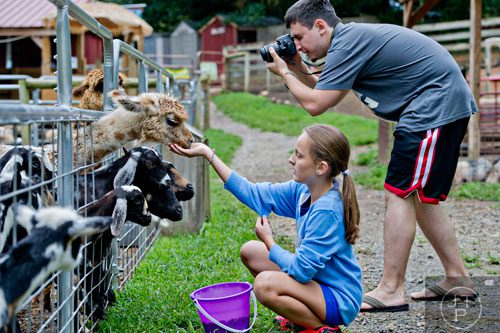Evelyn Krakovski (left) feeds some of the goats, alpacas and llamas while her brother Lev takes photographs at the North Georgia Zoo and Petting Farm in Cleveland on Sunday, August 10, 2014. 