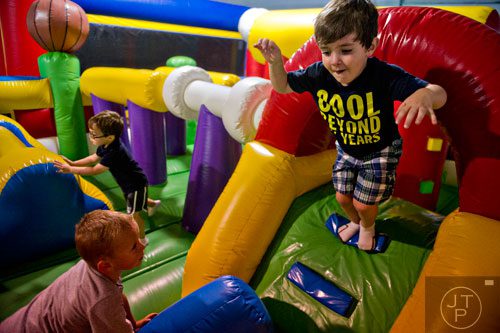 Preston Dalton (right) leaps towards Liam Duchnowski as they play with Jake Grabowski on one of the inflatables at Catch Air in Johns Creek on Thursday, August 14, 2014.  