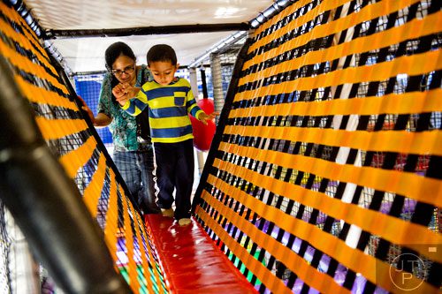 Rudra Rathod (right) climbs over obstacles in the three story space tower with the help of his mother Disha at Catch Air in Johns Creek on Thursday, August 14, 2014.   