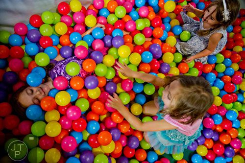 Ava Goldman (left) is covered in plastic balls by her sister Lainey and cousin Leighton Tritt inside the three story space tower at Catch Air in Johns Creek on Thursday, August 14, 2014. 