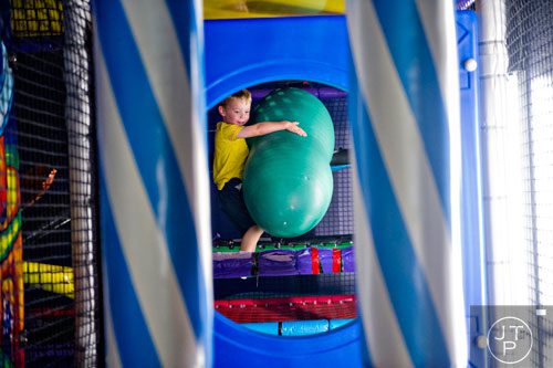 Sean Purvis carries a toy as he climbs over obstacles in the three story space tower at Catch Air in Johns Creek on Thursday, August 14, 2014. 