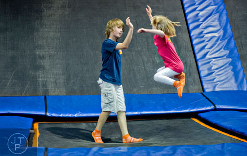 Sara Kate Mulligan (right) bounces into the air to give her brother Hugo a high five at Sky Zone indoor trampoline park in Suwanee on Friday, August 15, 2014.  