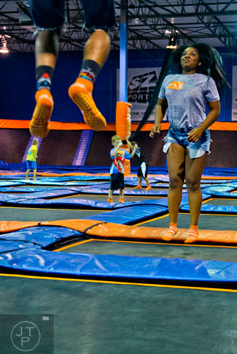 Asia Eraper (right) bounces into the air with Sean Davis (feet) at Sky Zone indoor trampoline park in Suwanee on Friday, August 15, 2014.