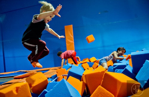 Oliver Edwards (left) follows Jasmine Donahue-Hutcherson and her brother Xavier as he flies into a foam pit at Sky Zone indoor trampoline park in Suwanee on Friday, August 15, 2014.  