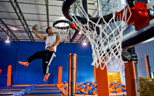 Malcolm Reid bounces into the air as he slams a basketball through the hoop at Sky Zone indoor trampoline park in Suwanee on Friday, August 15, 2014.