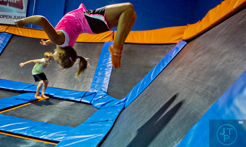 Rylee Boyd (right) does a back flip off of a wall trampoline as she bounces with Andrew Urnetz at Sky Zone indoor trampoline park in Suwanee on Friday, August 15, 2014.  