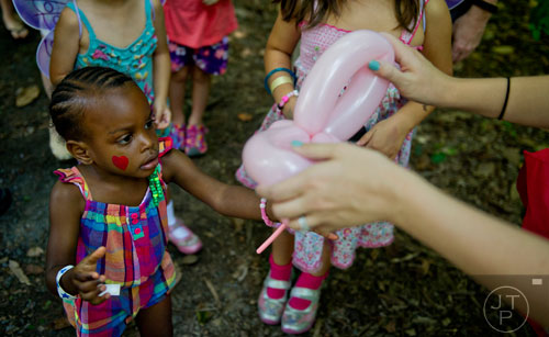 Paris Stegall (left) is handed a pink butterfly balloon animal by Victoria Brown during the Butterfly Festival at the Dunwoody Nature Center on Saturday, August 16, 2014. 