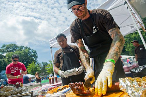Derek Lord (right) cuts a rack of ribs for Ezequiel Palacios during the Decatur BBQ, Blues & Bluegrass Festival at Harmony Park in Decatur on Saturday, August 16, 2014. 