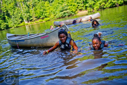 Nia Doyley (right) and Adjoa Baah tow their canoe back to shore at Camp Timber Ridge in Mableton on Thursday, July 17, 2014. 