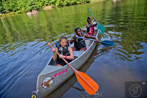 Hannah Todd (left), Trinity Lockett and Layla Doyley paddle away from shore in their canoe at Camp Timber Ridge in Mableton on Thursday, July 17, 2014. 