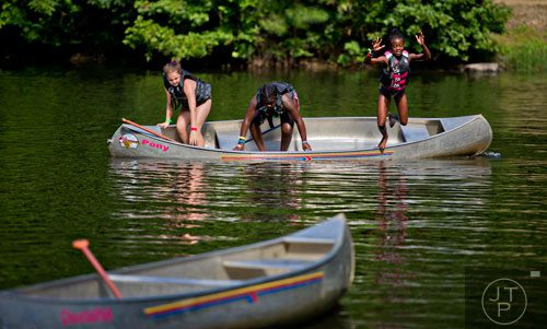 Layla Doyley (right) jumps into the lake at Camp Timber Ridge in Mableton as fellow campers Trinity Lockett and Hannah Todd try to steady their canoe on Thursday, July 17, 2014. 