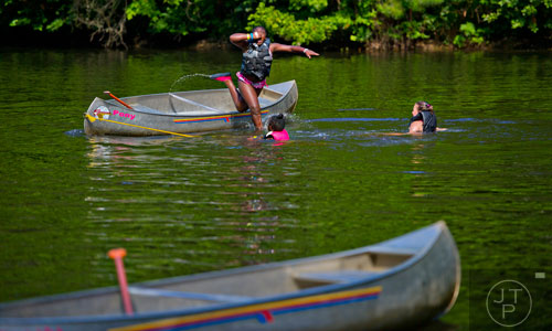 Trinity Lockett (left) jumps from a canoe into the lake at Camp Timber Ridge in Mableton as fellow campers Layla Doyley and Hannah Todd watch on Thursday, July 17, 2014. 