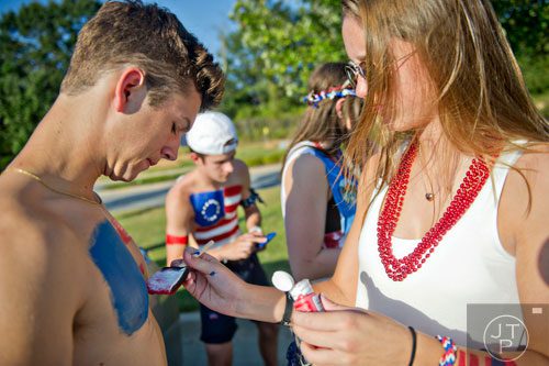 Grayson's Andrew Falgiano (left) has his chest painted by Ella Stevens as Evan Lynch paints Sarah Cotter's back before their game against Gainesville on Friday, August 29, 2014.   