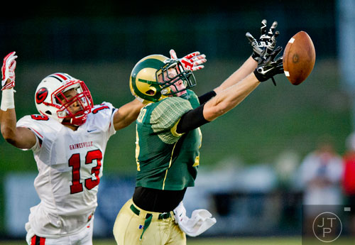 The ball slips through the fingers of Grayson's Hunter Schuessler (7) as Gainesville's Rodney Lackey (13) tries to break up the pass on Friday, August 29, 2014.