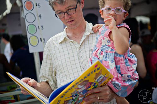 Judy Moore (right) is held by her father Leighton as he looks at a children's book during the AJC Decatur Book Festival on Saturday, August 30, 2014.