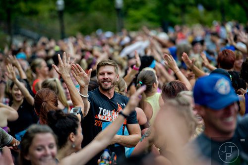 Joel Huff (left) gives out high fives as he stretches with the other participants of Wanderlust 108 at Piedmont Park in Atlanta on Sunday, September 28, 2014. 