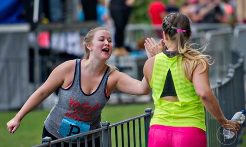 Sarah Pyke (left) gives Lindsay Schaaf a high five as she nears the finish line during the 5k portion of Wanderlust 108 at Piedmont Park in Atlanta on Sunday, September 28, 2014. 