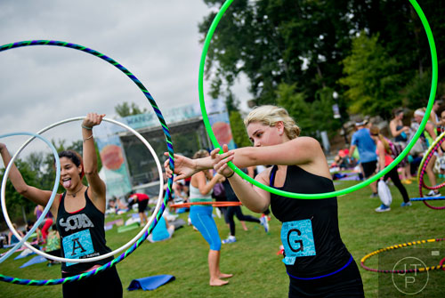 Michelle Higbee (right) and Nicole Espinal work out with hula hoops as they wait for the meditation portion of the event to begin during Wanderlust 108 at Piedmont Park in Atlanta on Sunday, September 28, 2014. 