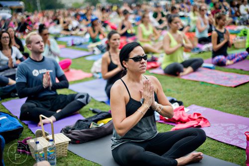 Chris Shope (right) stretches into a yoga pose during Wanderlust 108 at Piedmont Park in Atlanta on Sunday, September 28, 2014. 
