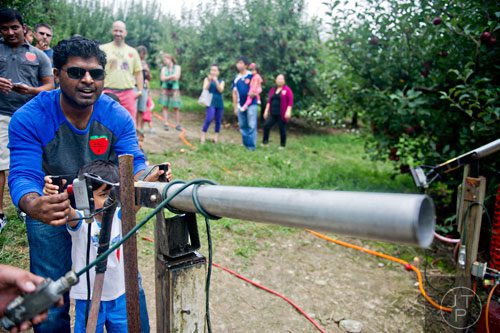 Srinivas Sudi (left) helps his son Rithvik fire an apple cannon at B.J. Reece Orchards in Ellijay on Sunday, September 14, 2014.  