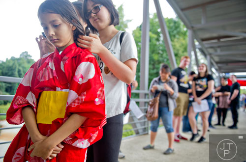 Sophia Roland (left) waits in line for the opening of the 2014 JapanFest at the Gwinnett Center in Duluth as her sister Isabella plays with her hair on Saturday, September 20, 2014. 