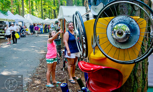 Ella Kraselsky (left) points out a piece of artwork to her mother Amy as they walk past artist booths during the 46th annual Yellow Daisy Festival at Stone Mountain Park on Saturday, September 6, 2014. 