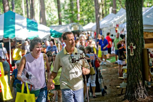 Sarah Dekutowski (left) holds hands with her husband John as they check out the artist booths during the 46th annual Yellow Daisy Festival at Stone Mountain Park on Saturday, September 6, 2014. 