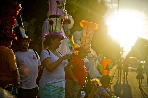 The sun starts to set as Kimberly Aguirre (center) waits for the start of the Atlanta Beltline Lantern Parade on Saturday, September 6, 2014. 