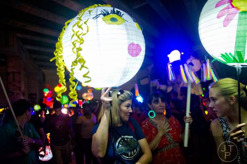 Kelly Myers (center) carries a lantern as she talks with friends during the Atlanta Beltline Lantern Parade on Saturday, September 6, 2014. 