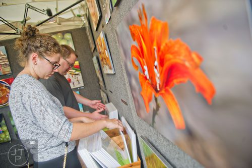 Anna Wrigley (left) and Bryan Miller look at photographs in Lorri Honeycutt's booth during the Atlanta Arts Festival at Piedmont Park on Saturday, September 13, 2014.