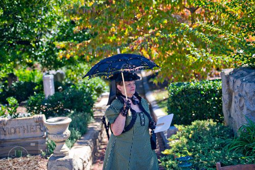 Gail Robinson shades herself from the sun with a parisol as she walks through Oakland Cemetery in Atlanta during the 35th annual Sunday in the Park on Sunday, October 5, 2014. 