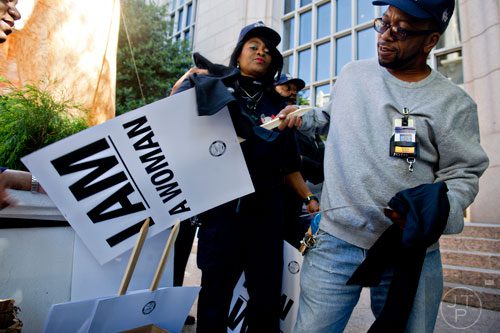 Wilbert Bryant (right) and Angela Stevens, both rail operators, grab signs and t-shirts before rallying in front of the law offices of MARTA Board Chair Robbie Ashe off of W. Peachtree St. in Atlanta on Monday, October 6, 2014. 