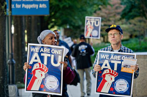 Salina Arnold (left) and Bob Braxton carry signs and chant with around 150 other MARTA employees and retirees as they rally in front of the law offices of MARTA Board Chair Robbie Ashe off of W. Peachtree St. in Atlanta on Monday, October 6, 2014. 