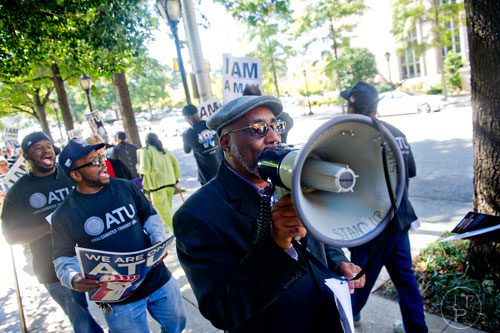 Greg Fann (center) uses a bullhorn to lead chants with around 150 MARTA employees and retirees as they rally in front of the law offices of MARTA Board Chair Robbie Ashe off of W. Peachtree St. in Atlanta on Monday, October 6, 2014. 