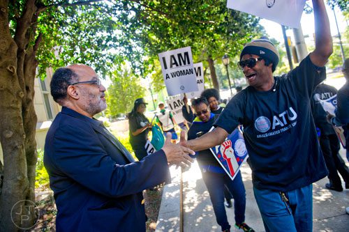 Senator Vincent Fort (left) shakes hands with James St. Ykes as he and around 150 other MARTA employees and retirees rally in front of the law offices of MARTA Board Chair Robbie Ashe off of W. Peachtree St. in Atlanta on Monday, October 6, 2014. 
