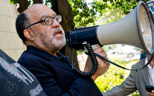 Senator Vincent Fort uses a bullhorn to speak to around 150 other MARTA employees and retirees as they rally in front of the law offices of MARTA Board Chair Robbie Ashe off of W. Peachtree St. in Atlanta on Monday, October 6, 2014. 
