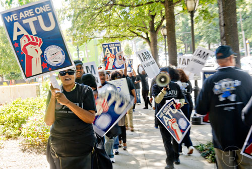 Gail Smith (left) walks the sidewalk carrying a sign and chanting with around 150 other MARTA employees and retirees as they rally in front of the law offices of MARTA Board Chair Robbie Ashe off of W. Peachtree St. in Atlanta on Monday, October 6, 2014. 