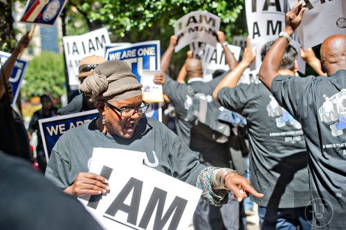 Yvette Brown walks the sidewalk carrying a sign and chanting with around 150 other MARTA employees and retirees as they rally in front of the law offices of MARTA Board Chair Robbie Ashe off of W. Peachtree St. in Atlanta on Monday, October 6, 2014. 