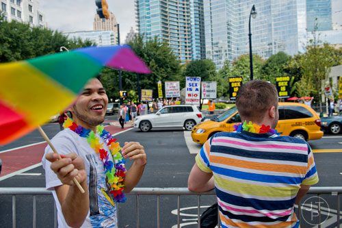 William Avilez (left) waves a rainbow colored flag as he and his partner Tristan Imhof react to the protestors across the street as they wait for the start of the Atlanta Pride Parade on Sunday, October 12, 2014. 