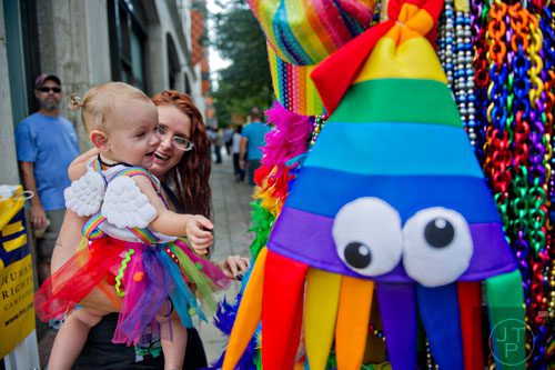 Charlee Martinez (left) reaches for a rainbow colored toy as she is held by her mother Krimsen as they wait for the start of the Atlanta Pride Parade on Sunday, October 12, 2014. 