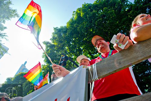 Ricky Howell (center) waves a rainbow flag as he rides a float down Peachtree St. during the Atlanta Pride Parade on Sunday, October 12, 2014. 