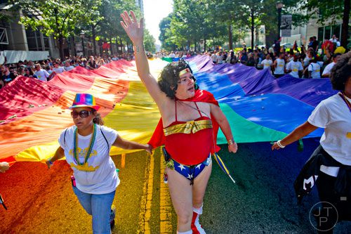 Christylynn Rosser (center) and Ayeisha Quinones help carry the gigantic rainbow flag down Peachtree St. during the Atlanta Pride Parade on Sunday, October 12, 2014. 