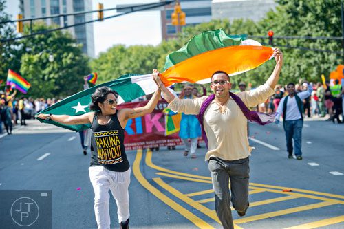 Lalita Bala (left) and Himanshu Mishra carry flags over their heads as they run down 10th St. during the Atlanta Pride Parade on Sunday, October 12, 2014. 