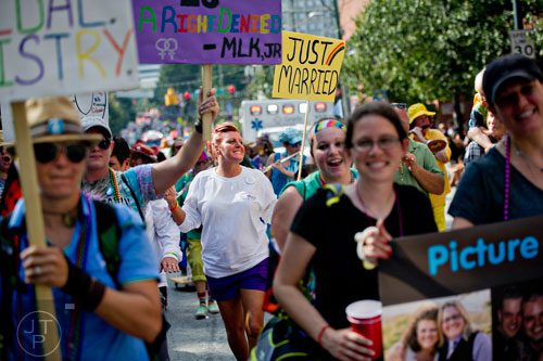 Christy Busby (center) marches down 10th St. holding a just married sign during the Atlanta Pride Parade on Sunday, October 12, 2014. 