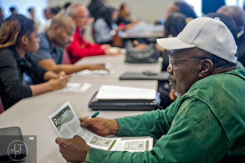 William McKenzie (right) looks over a pamphlet on resumes as he waits with other hopeful applicants for the start of the South Clayton Job Fair at the South Clayton Recreation Center in Hampton on Tuesday, September 30, 2014. 